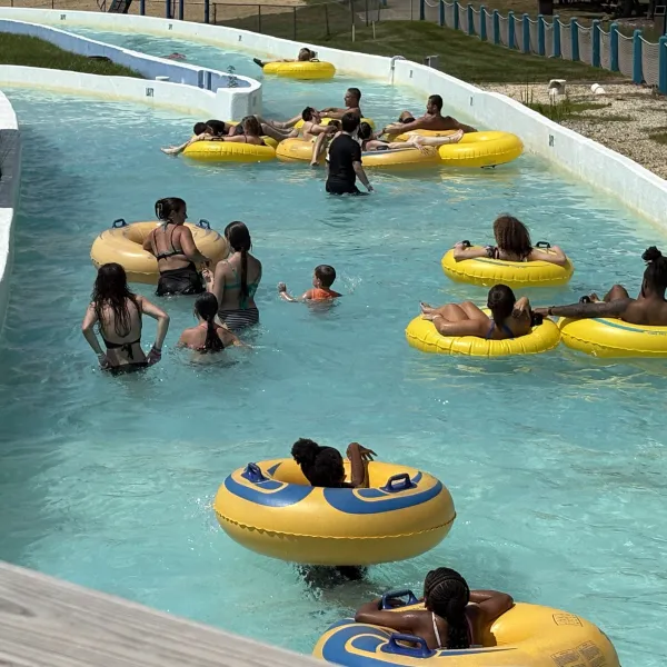 People enjoying a lazy river ride at a water park on yellow inner tubes.