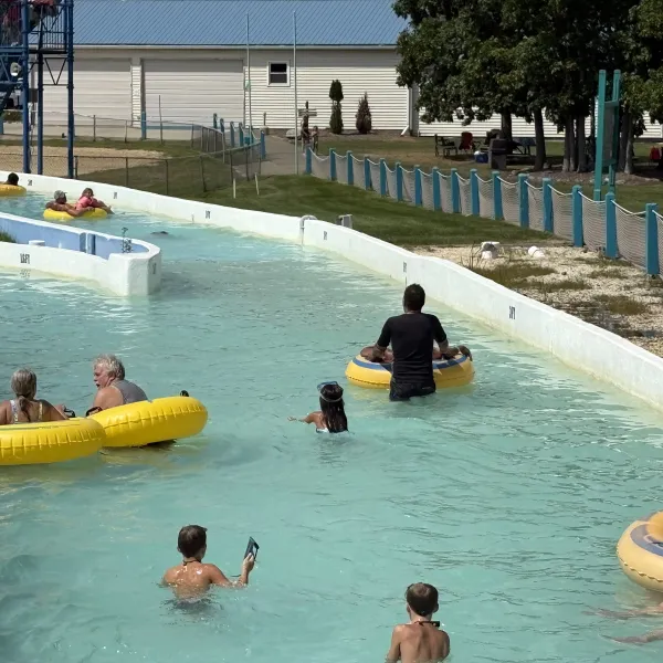 People enjoy a lazy river ride in a water park using yellow inner tubes.