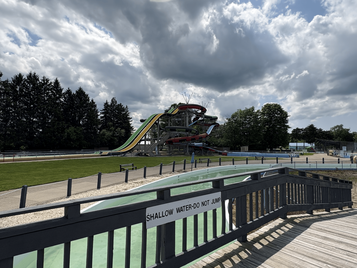 Outdoor water park with slides, empty pools, under cloudy sky.