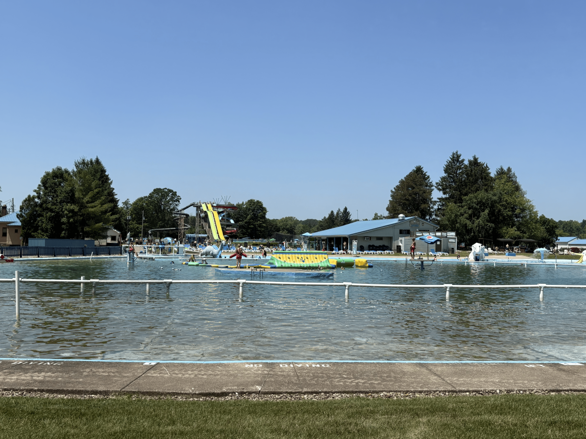 Outdoor water park with slides, pool, and trees under clear blue sky.
